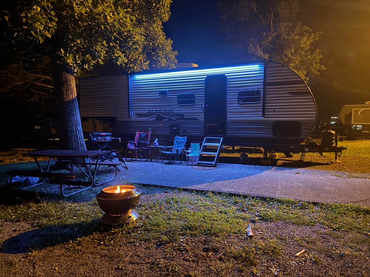 Our family campsite at night with chairs and a contained campfire