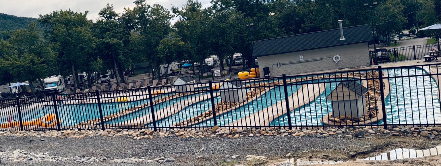 Fenced lazy river at Clabough's Campground with floats, seating, trees, and RV sites in the background.