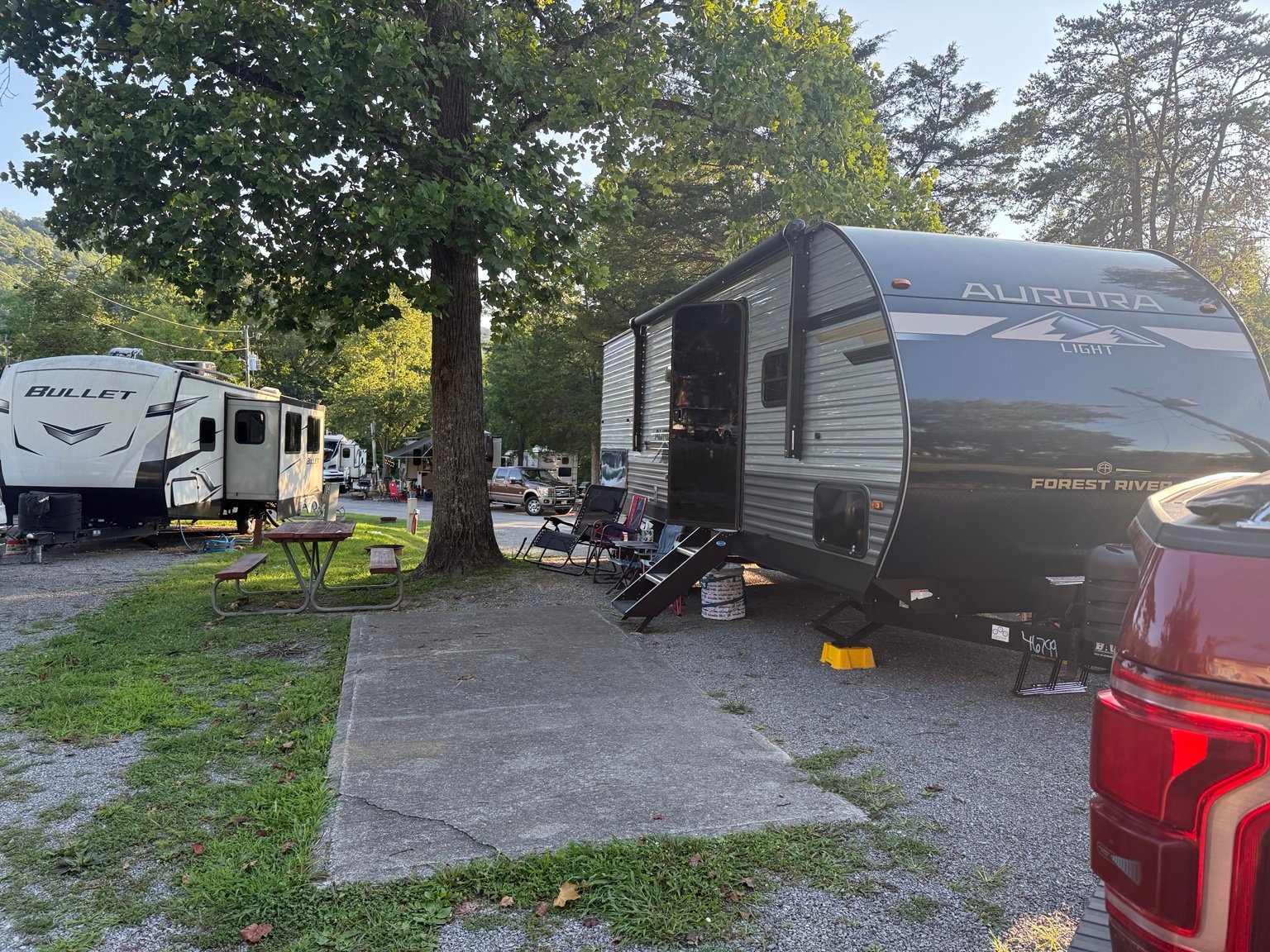 Site 73 at Clabough's Campground showing the travel trailer, patio, picnic table, shade tree, and nearby RV sites.