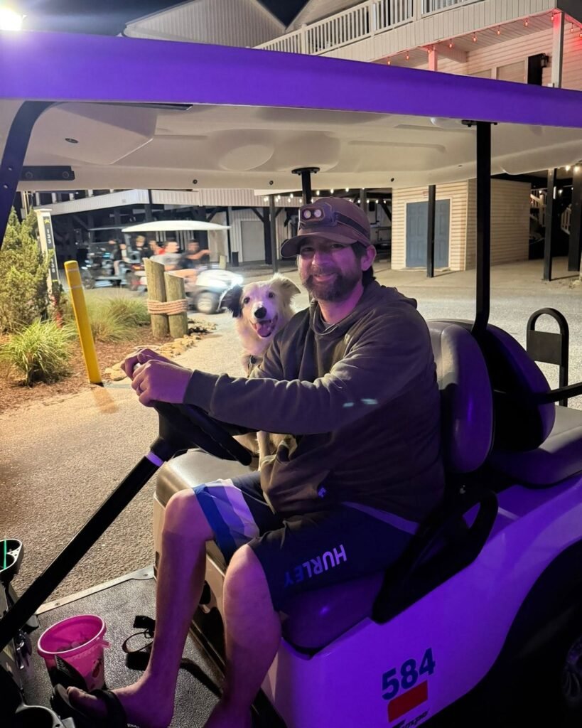 Jason and border collie Dolly riding an Ocean Lakes golf cart at night