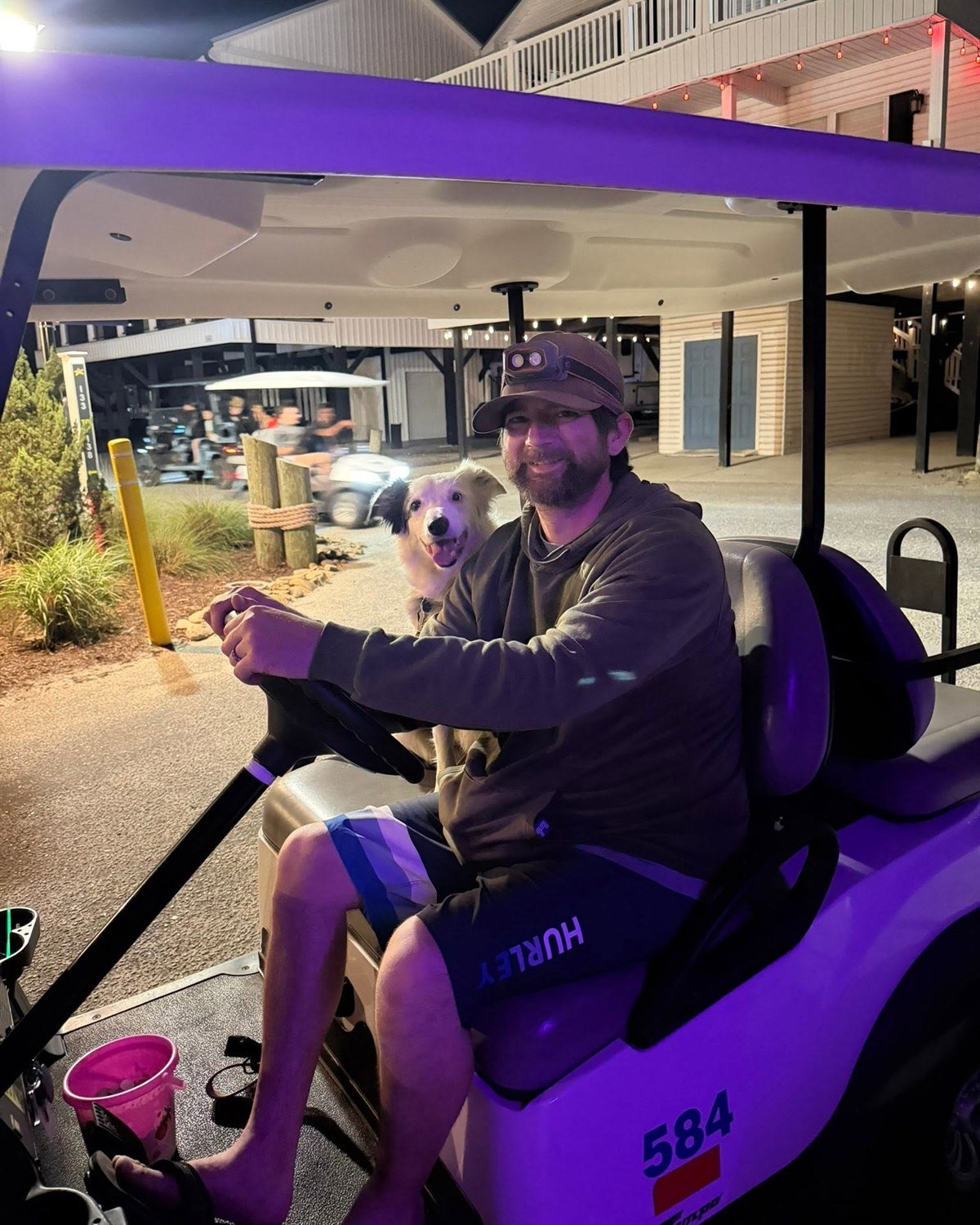 Jason and border collie Dolly riding an Ocean Lakes golf cart at night